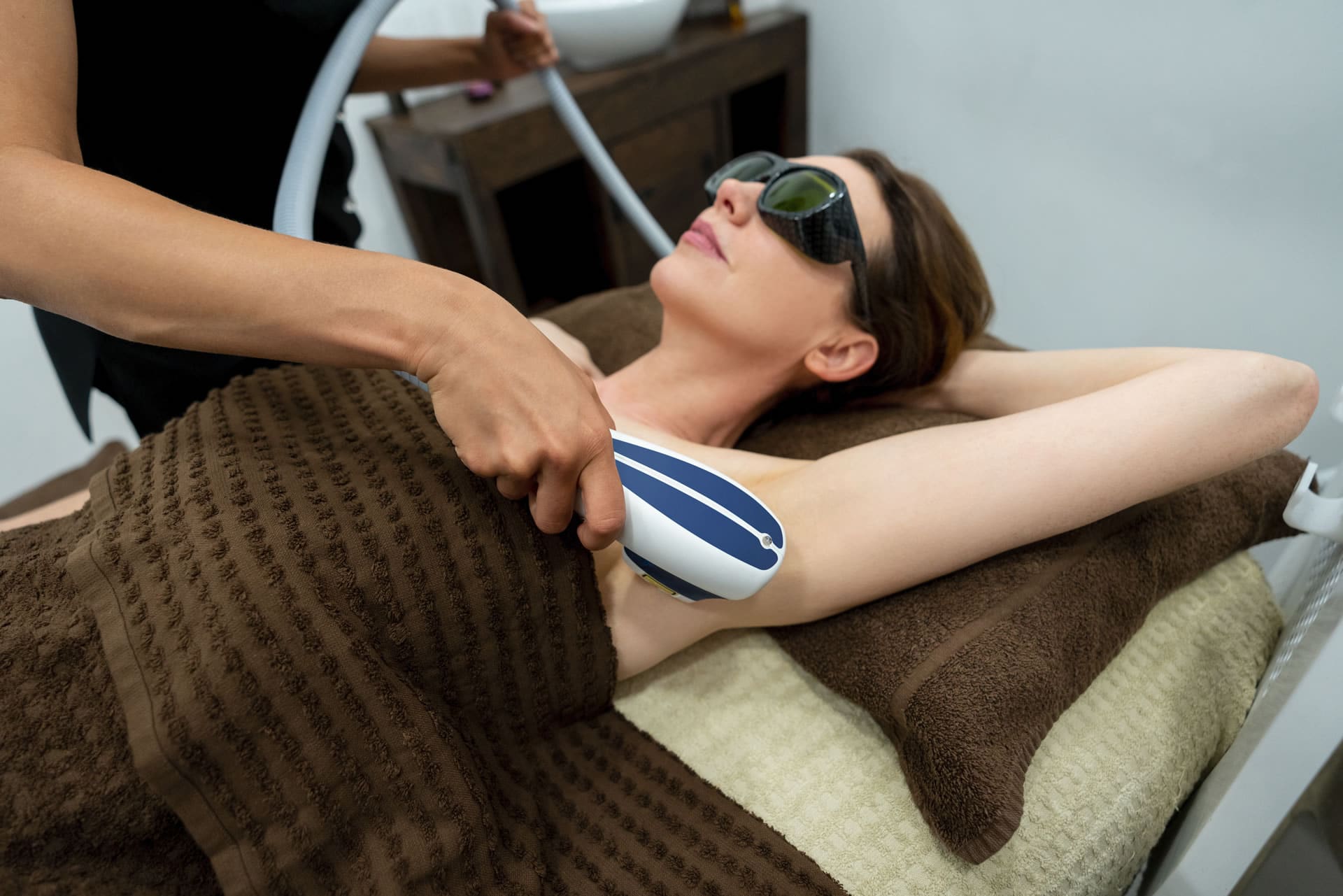 woman laying down wearing goggles receiving sciton laser hair removal on armpit