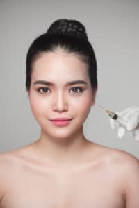Beautiful asian woman gets beauty dermal filler injections. Face aging injection.