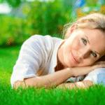 smiling woman lying on a grass outdoor.
